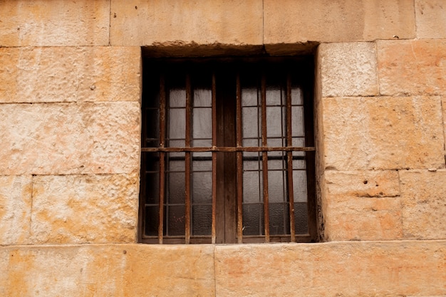 Fenêtre avec des grilles rouillées sur une façade en pierre