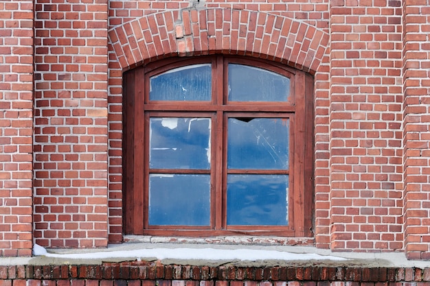 Une fenêtre en verre arquée sur le vieux mur de briques rouges