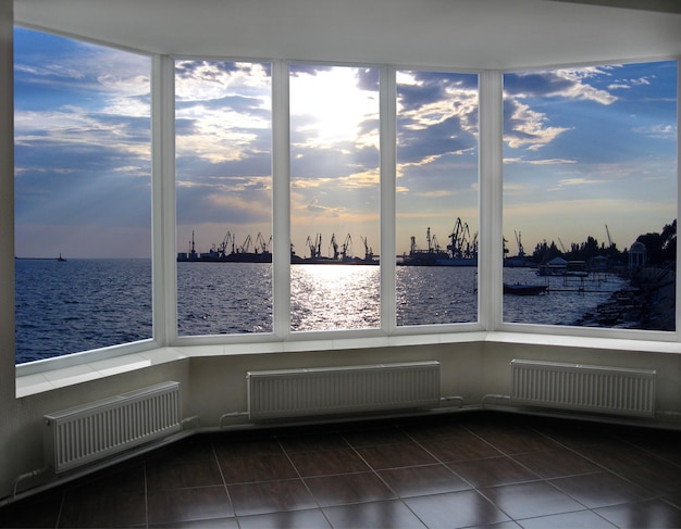 fenêtre avec vue sur les quais et les grues du port maritime du soir à Berdyansk