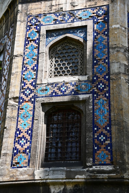 Photo fenêtres avec de beaux treillis ajourés mur d'un immeuble ancien avec des tuiles colorées