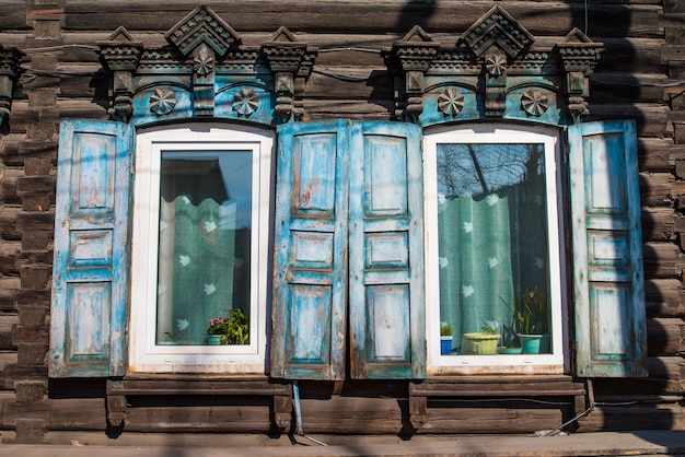 Fenêtres en bois avec volets et motifs sculptés sur les fenêtres dans une maison en bois rustique