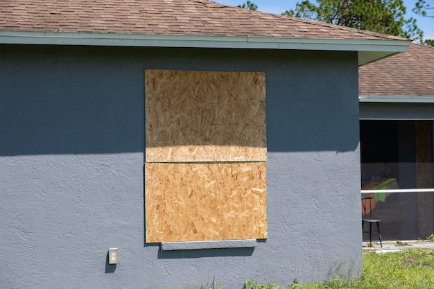 Fenêtres bordées avec des volets en contreplaqué pour la protection contre les ouragans des maisons résidentielles Mesures de protection avant une catastrophe naturelle en Floride