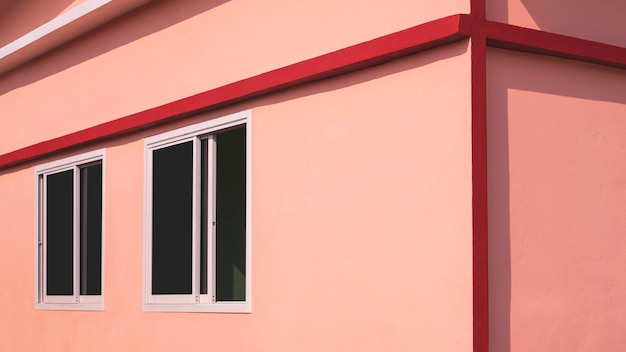 Fenêtres coulissantes en verre sur mur de béton orange avec bord rouge de maison moderne en vue latérale en perspective