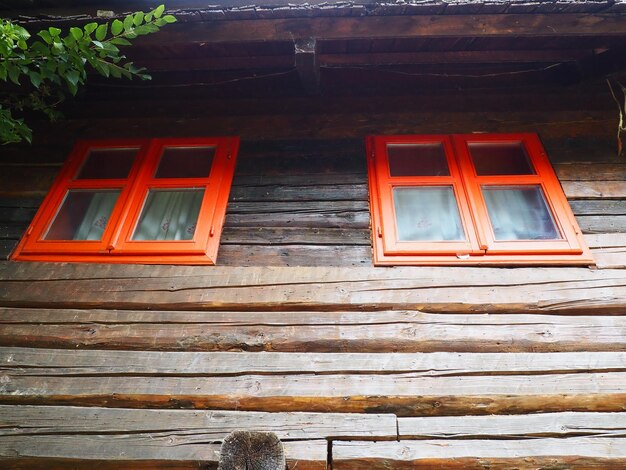 Fenêtres ethno avec un cadre en bois rouge Extérieur de la maison d'époque Complexe architectural Stanisici Cabane en rondins Bâtiment Izba dans une zone rurale boisée sur le territoire de la colonie des Slaves de l'Est