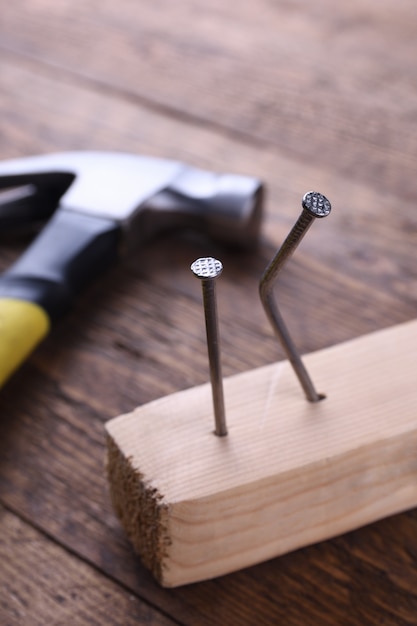 Fer à marteau, ruban centimétrique et clous sur table en bois