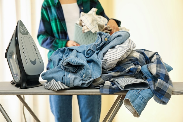 Fer sur planche à repasser et femme avec panier de linge