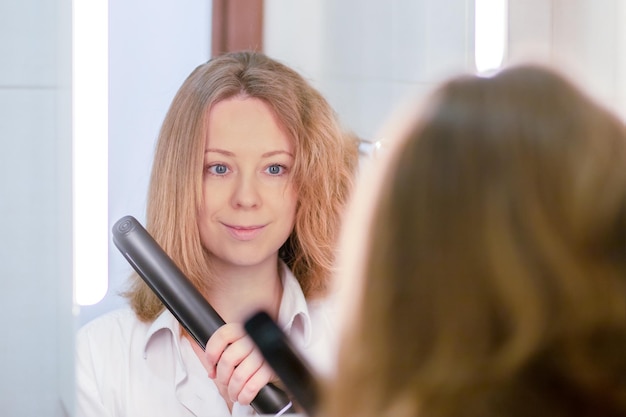 Photo fer pour les cheveux pour les redresser et les lisser femme avec avant et après dans la salle de bain