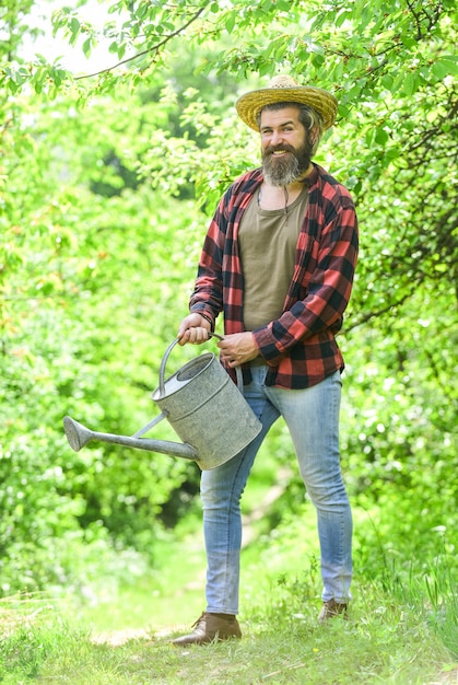 Ferme d'été. agriculture et concept de travail difficile. Concept de jardinage ou de plantation. Homme utilisant un grand arrosoir pour la plantation. verser l'eau. homme avec arrosoir. jardinage et arrosage des plantes.