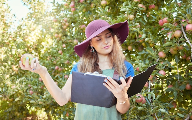 Ferme de recherche et agriculteur lisant sur la culture des pommes dans un verger pour une agriculture et une croissance durables Femme avec des fruits à la campagne pour une analyse d'inspection et des connaissances sur la nature