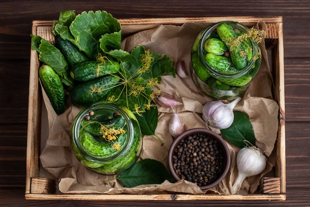 Fermentation des concombres dans des bocaux en verre. Concombres crus, fleurs d'aneth, feuille de cerisier, feuille de raifort, épices et herbes sur un plateau