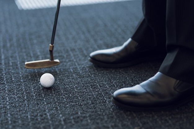 Photo fermer. club de golf et balle de golf sur un tapis gris.