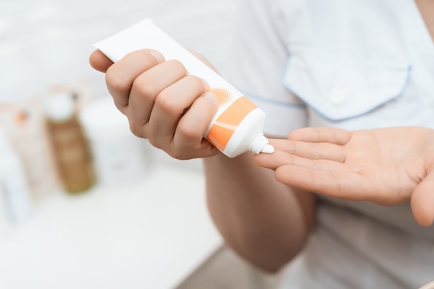 Fermer. Le docteur met sur les mains une crème spéciale pour le massage.