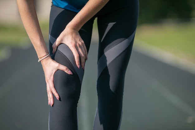 Fermer. Femme sportive ayant une blessure à la cheville en piste de course. Concept de santé et de sport.