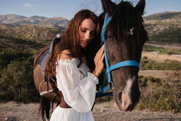 Fermer. Une fille romantique embrasse son cheval sur fond de paysage de montagne. Le concept de l'équitation. Photographie artistique. Couverture prête à l'emploi pour livres et magazines.