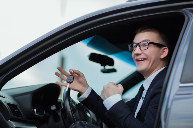 Fermer. homme d'affaires heureux détenant les clés de sa nouvelle voiture