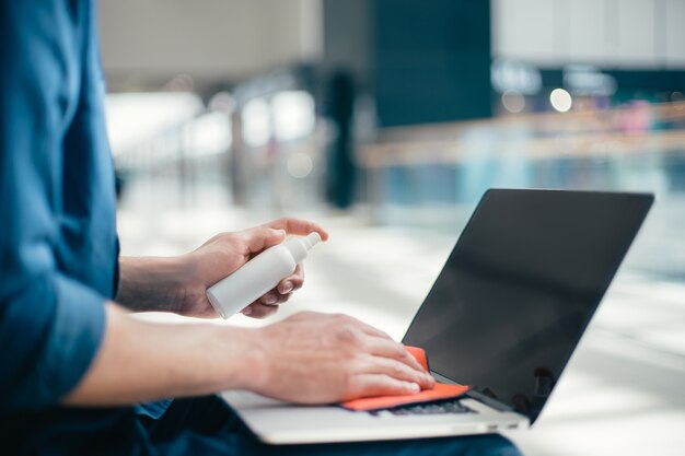 Fermer. homme essuyant la poussière du clavier de l'ordinateur portable.