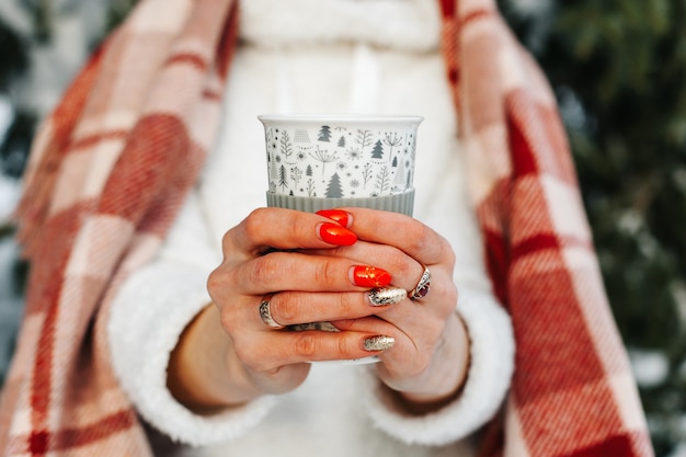 Fermer. homme et femme tenant des tasses de chocolat chaud avec de la crème dans la forêt d'hiver