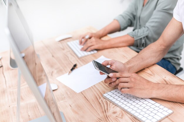 Fermer. jeunes employés regardant l'écran de son smartphone. les gens et la technologie