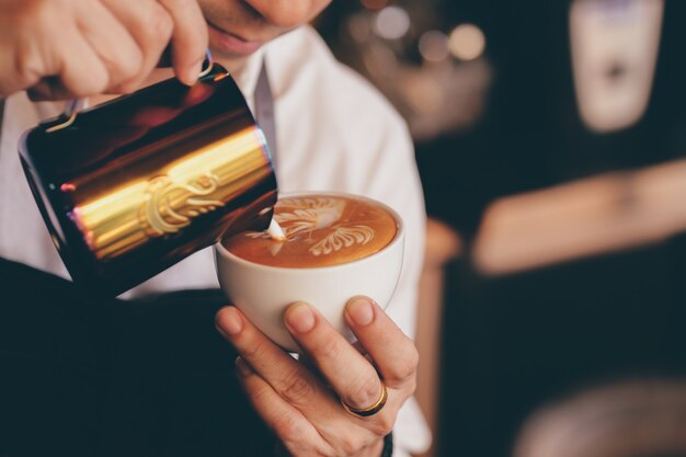 fermer la main de barista faisant une tasse de café.