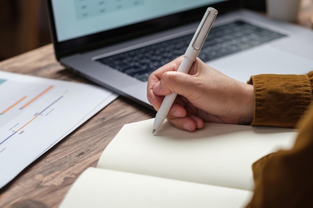 Fermer la main de femme uop écrivant sur un ordinateur portable au bureau de travail à la maison