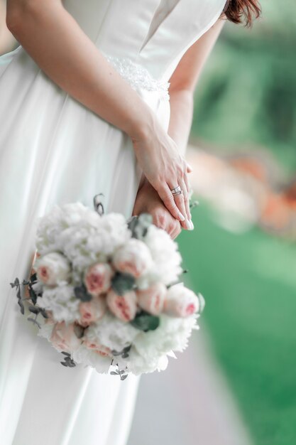 Fermer. la mariée tient le bouquet de mariage derrière son dos.