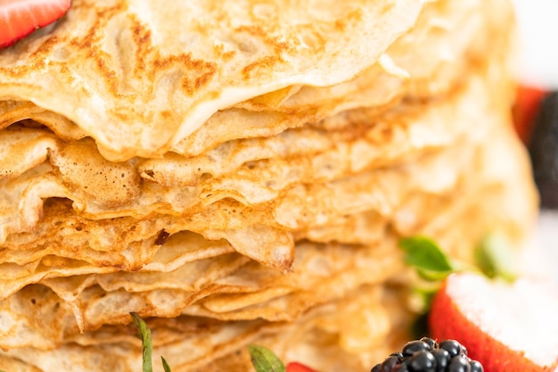 Fermer. Pile de crêpes fraîchement cuites au four avec des baies sur un stand de gâteau.