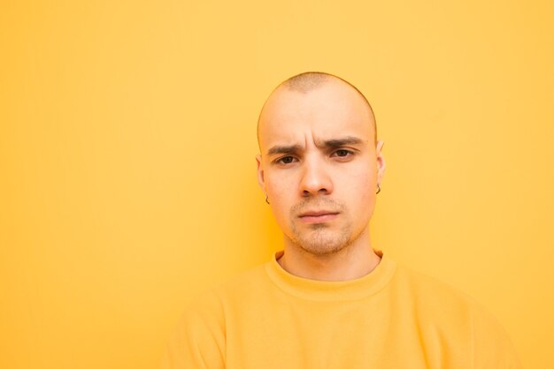 Fermer le portrait d'un mec original malheureux dans des vêtements élégants sur un jaune