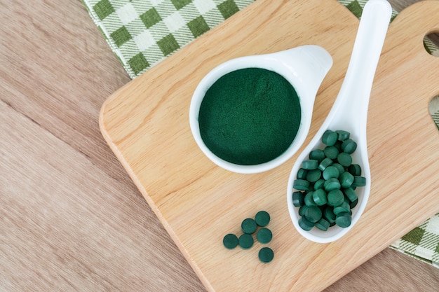 Fermer une poudre de spiruline dans un bol et des pilules de spiruline, un régime alimentaire sain et un concept de nutrition détox