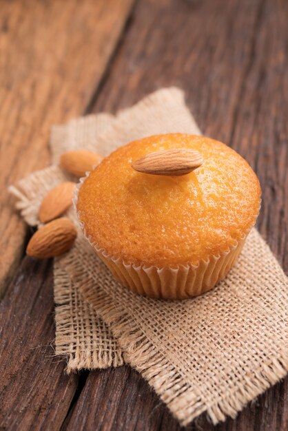 Fermer une tasse de gâteau aux amandes contre le tissu du sac sur la table en bois