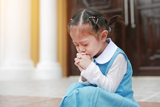 Fermer les yeux petite fille asiatique en uniforme étudiant en prière. Spiritualité et religion