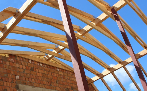 Fermes de toit non recouvertes de tuile céramique sur maison individuelle en construction, éléments de toiture apparents, voliges, contre-lattages, chevrons. Système de toiture industrielle en bois, poutres et bardeaux.