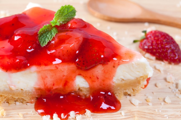 Fermez le gâteau aux fraises sur une assiette en bois sur la table en bois.