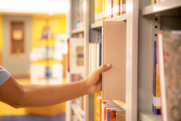 Fermez la main en choisissant un livre dans la bibliothèque.