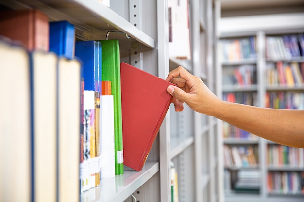 Fermez la main en choisissant un livre dans une étagère