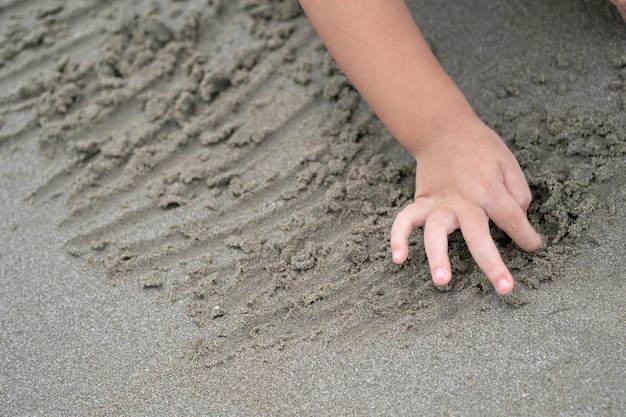 Fermez la main et les doigts de l'enfant, jouez et apprenez à la plage.