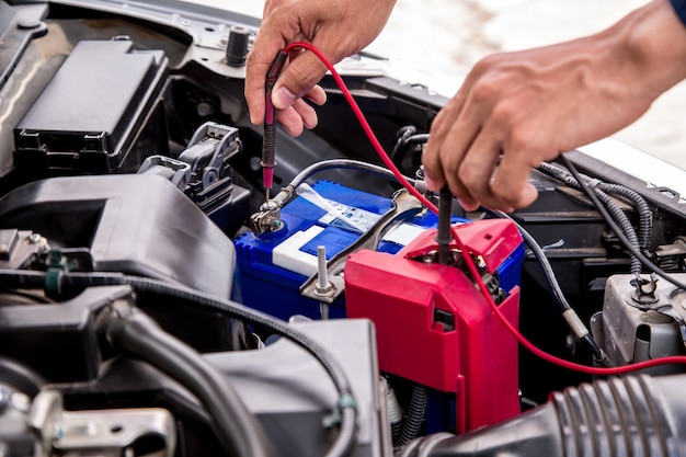 Fermez la main du mécanicien automobile à l'aide de la mesure de la batterie de la voiture.