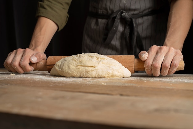 Photo fermez les mains à l'aide d'un rouleau à pâtisserie