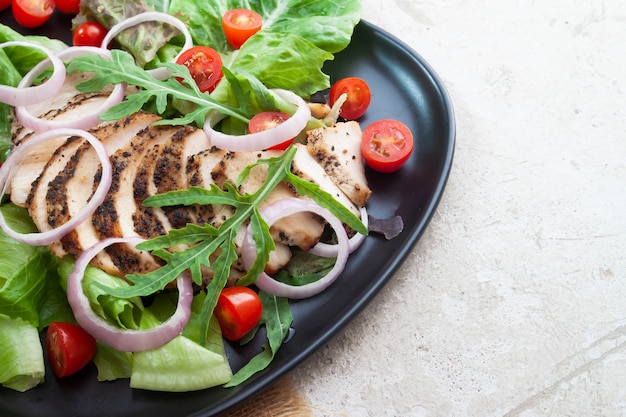 Fermez une salade saine avec du poulet grillé, des oignons et des tomates. La nourriture saine.