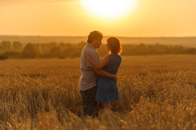 Un fermier adulte et sa femme se serrent dans leur champ de blé.