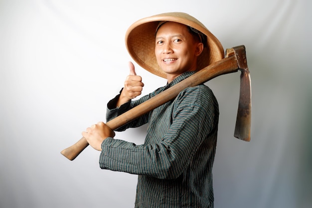 Photo un fermier asiatique heureux portant un lurik et un caping donnant un pouce isolé sur un fond blanc