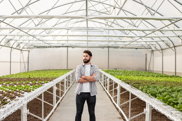 Fermier confiant debout dans une serre avec des plantes