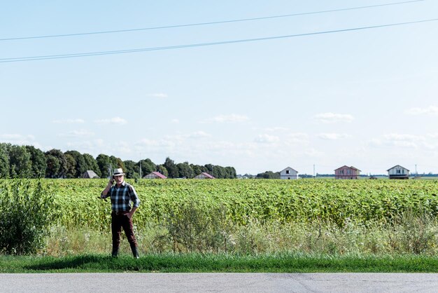 Fermier indépendant barbu parlant sur smartphone dans le champ