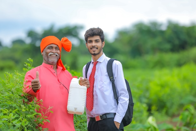 Fermier indien avec agronome au champ, agriculteur et agronome montrant une bouteille d'engrais