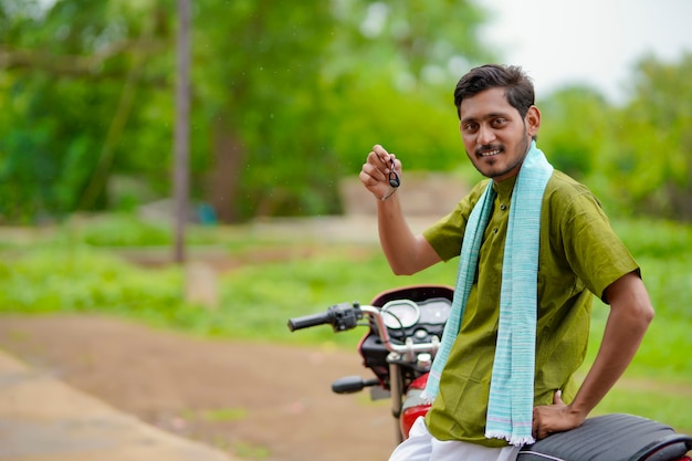 Fermier indien assis sur un vélo et montrant la clé