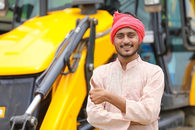 Fermier indien debout avec ses nouvelles machines de terrassement.