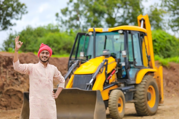 Fermier indien debout avec ses nouvelles machines de terrassement.