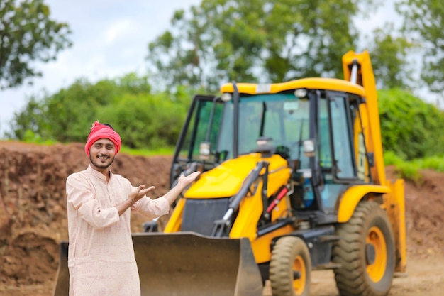 Fermier indien debout avec ses nouvelles machines de terrassement.