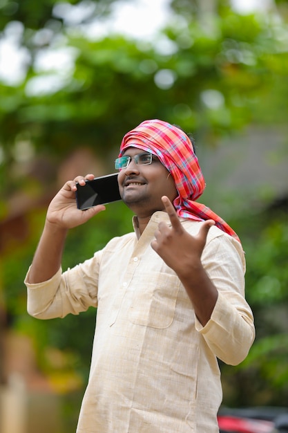 Fermier indien parlant sur smartphone à la maison.