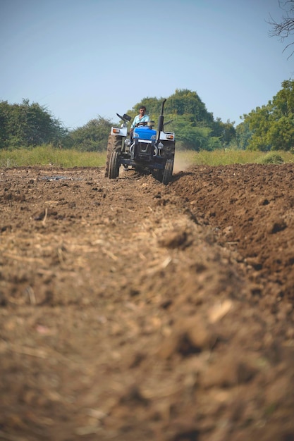 Fermier indien travaillant avec un tracteur dans le domaine de l'agriculture.