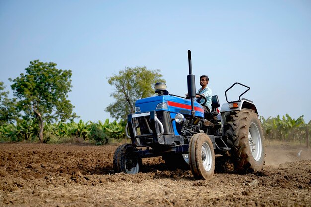 Fermier indien travaillant avec un tracteur dans le domaine de l'agriculture.